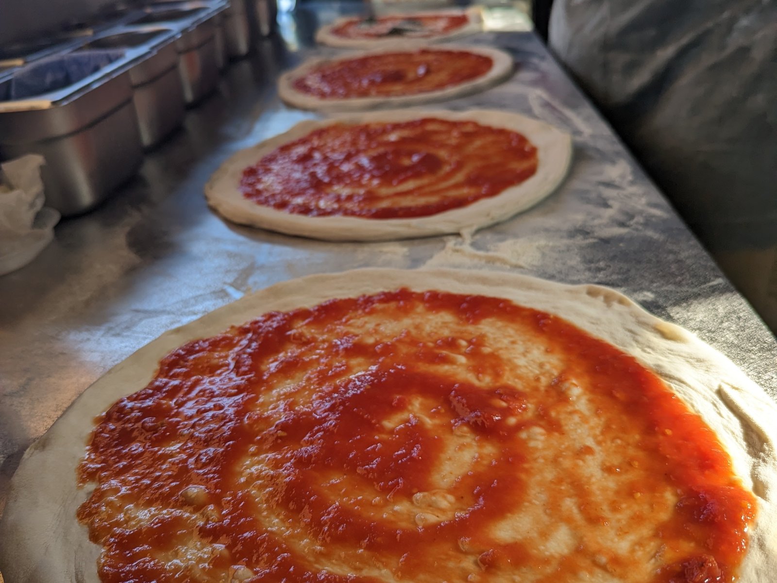 Hand-stretched pizza bases with hand-spread tomato sauce, ready for toppings
